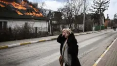 কিয়েভের ইরপিনে আগুনে পোড়া বাড়ির সামনে এক নারী