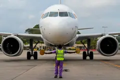In this picture taken on September 26, 2022, a member of ground staff directs a SriLankan Airlines aircraft at the Colombo International Airport in Katunayake. - Dozens of state-owned Sri Lankan companies employing tens of thousands of people could be downsized or closed as part of an IMF bailout of the bankrupt country, with the country's airline top of the list for reform. - TO GO WITH SriLanka-economy-aviation-privatisation, FOCUS by Amal JAYASINGHE 