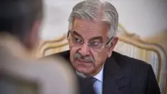 خواجه آصف وزیر دفاع پاکستان - با دریشی سیاه رنگ خط‌دار و پیراهن سفید