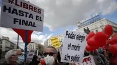 Na Espanha, manifestantes protestam a favor da eutanásia. Eles carregam cartazes com os dizeres "Livre até o fim" e "O poder de escolher morrer sem sofrimento".