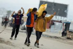 Homens carregando sacos nas costas