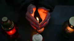 руки, які тримають свічки 