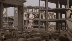 هياكل خرسانية لمبانٍ سكنية مدمرة، محاطة بالأنقاض، في جوبر، وهي قرية تقع على مشارف دمشق