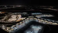 Vista aérea noturna da janela de um avião mostra diversas aeronaves estacionadas no Aeroporto Internacional Zayed, em Abu Dhabi, nos Emirados Árabes Unidos