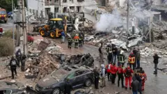 Socorristas removem escombros no local de um ataque russo contra um bairro residencial em Kiev, na Ucrânia