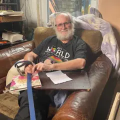 Jeremy Gavins sentado en un sillón de cuero en su casa con una carta en el regazo