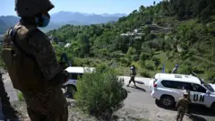 Bir Pakistan askeri, Kontrol Hattı'nı ziyarette bulunan Birleşmiş Milletler gözlemcilerine bakıyor