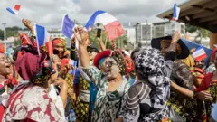 نساء من جزيرة مايوت يلوحن بالأعلام الفرنسية.