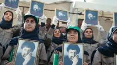 Wanawake waliovalia kofia za kijani kibichi, mitandio ya rangi nyeusi na sare za kaki wakiwa na picha za sura za Musa al-Sadr katika maandamano ya kuadhimisha kumbukumbu ya kutoweka kwake mwaka jana.