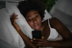 Une femme sur son portable dans son lit