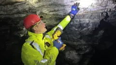 Eldur Olafsson, the chief executive of mining company Amaroq Minerals, points to gold in the rock