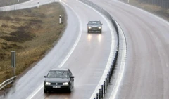 Voitures circulant sur une route à deux voies avec une barrière métallique