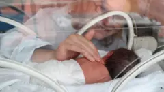 Küvezde prematüre bebek ve bir kadın