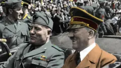 هتلر وموسوليني يركبان سيارة مكشوفة عبر شوارع ميونيخ أثناء زيارة الثاني لألمانيا عام 1941