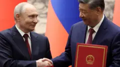 普京和习近平签署协议后握手。