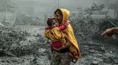 امرأة تحاول النجاة بطفلتها من القصف الإسرائيلي على غزة