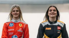 Two female F1 Academy drivers pose for a photo on a race track