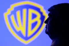 Miniatura em impressão 3D do rosto do presidente dos EUA, Donald Trump, posicionada em frente ao logotipo da Warner Bros