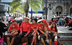Cinco indígenas gunas, vestidos com seus trajes tradicionais, sentados na Praça da Independência, no centro histórico da Cidade do Panamá, em 28 de setembro de 2025. (Foto: MARTIN BERNETTI/AFP via Getty Images)