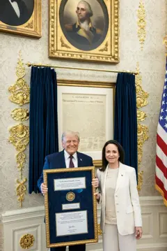 Trump con la medalla del Nobel de la Paz enmarcada, junto a María Corina Machado en la Casa Blanca.