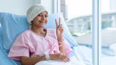 कॅन्सर रुग्ण हॉस्पिटलमधल्या बेडवरून vicrory साईन दाखवताना. 