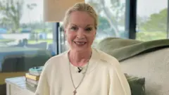 Mulher olha para a câmera com janela ao fundo