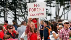 Мушкарци и жене на протесту држе пароле против вакцинације