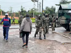 Une rue de Bamenda avec des hommes en uniforme militaire et un jeep.