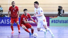 بازیکن ایران با لباس‌ سفید که توپ را در اختیار دارد و دو بازیکن افغانستان با لباس‌های سرخ در تلاش گرفتن توپ هستند.