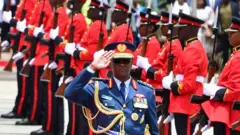 Umugaba mukuru w’ingabo za Kenya, Jenerali Francis Ogolla (hagati) akoze ikimenyetso, mu gihe Umwami w’Ubwongereza Charles III (utaboneka) na Perezida wa Kenya William Ruto (utaboneka) bari bageze ku mva y’umurwanyi utazwi mu muhango wo gushyira indabo mu busitani bwa Uhuru Gardens i Nairobi, ku itariki ya 31 Ukwakira (10) mu 2023. 