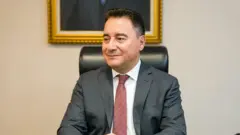 Ali Babacan üzerinde bir takım elbiseyle otururken