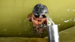 গরমে পানিতে ভিজছে এক শিশু