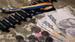 Колаж на тему фінансування армії. На тканині мілітарі - купюри 500 грн, патрони, синьо-жовта стрічка