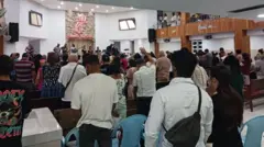 Pessoas de costas orando e erguendo as mãos