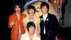 Четверо молодих учасників The Beatles стоять у кольорових сценічних костюмах на тлі великого глобуса.