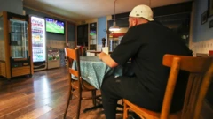 Homemgalo betanorestaurante almoçando enquanto assiste à TV