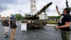 Мужчина фотографирует танк в центре Вильнюса.