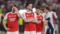 Abakinnyi ba Arsenal batatu barangajwe imbere na Declan Rice bahagaze bamanjiriwe, inyuma yabo hari abandi bakinnyi babiri ba Arsenal batagaragara neza mu maso bari kumwe n'umukinnyi wa Paris Saint-Germain, utagaragara neza mu maso, ufashe ku rutugu rw'umukinnyi wa Arsenal mu kumuhoza, nyuma yuko Paris Saint-Germain itsinze Arsenal ku mukino wa nyuma wa Champions League, ku wa gatandatu nijoro, ku itariki ya 30 Gicurasi (5) mu 2026.