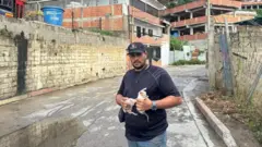 Homem venezuelano segura dois filhotesjogos para ganhar dinheiro no pix na horagato nas mãos