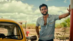 Wagner Moura apoiado em um poste