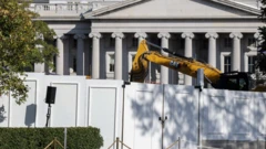 Строительная техника за забором, огораживающим Белый дом. Видно здание с колоннами