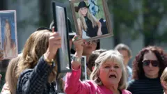 Lori Schott, una demandante que ha presentado una demanda contra empresas de redes sociales por la muerte de su hija, sostiene una fotografía mientras habla con los reporteros a las afueras del Tribunal Superior de Los Ángeles el 25 de marzo de 2026, en Los Ángeles, California.