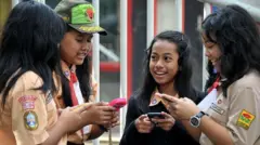 Anak-anak sekolah di Indonesia membuka Facebook di perangkat seluler mereka.