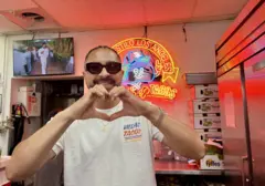 Victor fazendo coração com a mão em sua taqueria