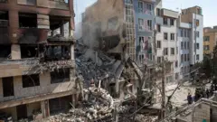 ساختمانی در تهران که در اثر حمله اسرائیل تخریب شده و نیروهای امداد در حال آواربرداری هستند