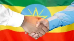 የተጨባበጡ እጆች ከጀርባ የኢትዮጵያ ባንዲራ 