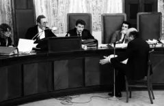 Roberto Calvi está sentado de frente para um juiz e outras pessoas