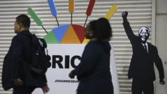 ደቡብ አፍሪካውያን የነጻነት ታጋዩን ኔልሰን ማንዴላን ምሥል በያዘው የብሪክስ ጉባኤ ፖስተር አጠገብ ሲያልፉ