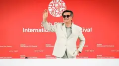 جعفر پناهی در حال دست تکان دادن به حاضران در کنفرانس خبری «یک تصادف ساده» در سی‌امین جشنواره بین‌المللی فیلم بوسان در شهر بوسان کره‌جنوبی