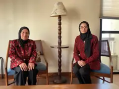 Nawal Abujayyab e Lozan sentadas em sala, posando para foto com sorrisos contidos